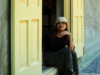 Portrait of young woman sitting at doorway