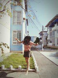 Rear view of woman standing by building in city