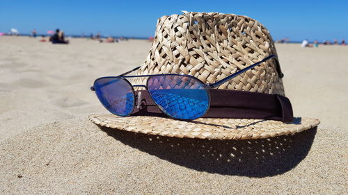 Close-up of sunglasses on sand at beach against sky