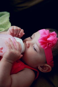 Close-up of baby girl drinking milk while napping on bed