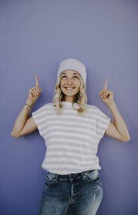 Portrait of young woman with arms crossed standing against blue background