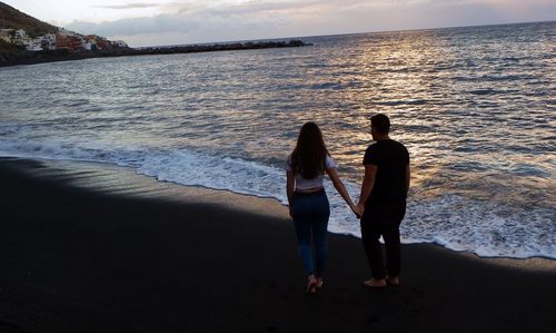 People on beach against sky during sunset