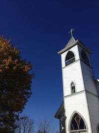 Low angle view of bell tower against clear blue sky