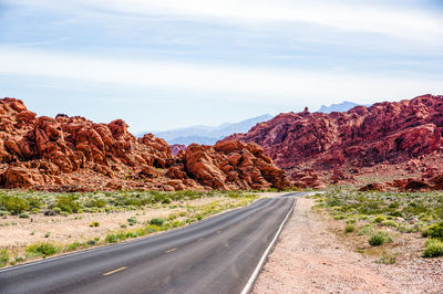 Road leading towards mountains against sky