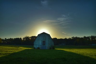 Scenic view of grassy field against sky at sunset