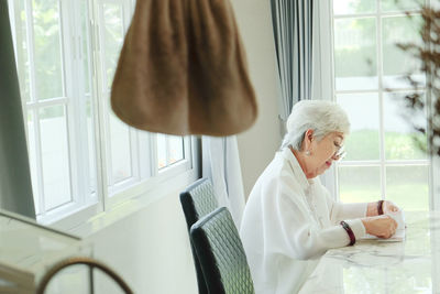 Senior woman reading book while sitting at home