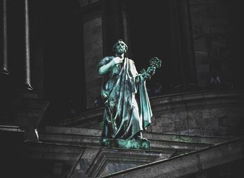 Statue of man and woman standing by staircase in building