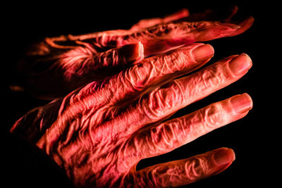 Close-up of wrinkled hands against black background