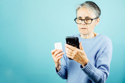 Young woman using mobile phone against blue background