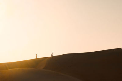 Silhouette person standing on desert against clear sky