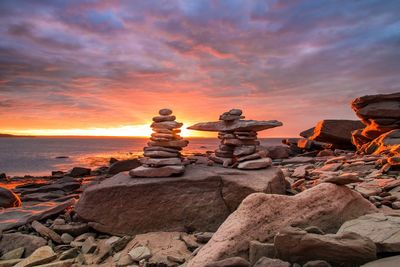 Stack of rocks on beach against sky during sunset