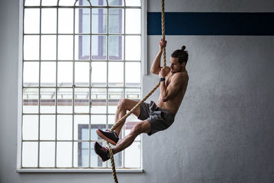 Side view of shirtless man on window