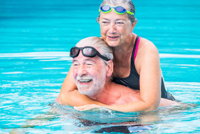 Smiling senior couple swimming in pool