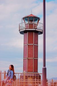 Low angle view of woman standing by tower against sky