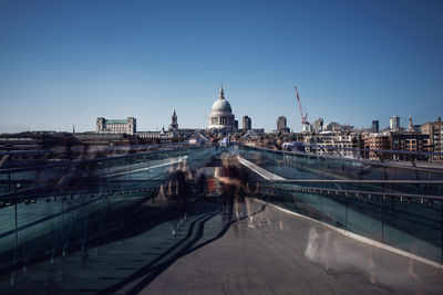 A crowd streams across millennium bridge towards st. pauls cathedral captured in a long exposure