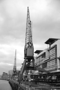 Low angle view of crane against cloudy sky