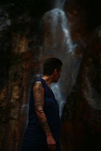 Woman with tattoo standing by waterfall