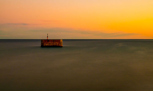Scenic view of sea against orange sky