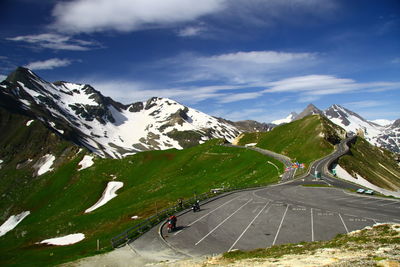 Man riding bicycle on road by mountain against sky