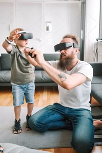 Caucasian father and son playing a game using vr headsets.ai generated