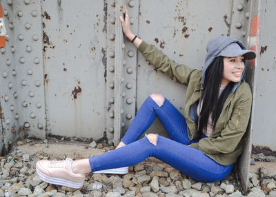 Portrait of a smiling young woman sitting on wall