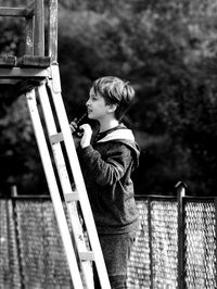 Side view of boy standing on ladder