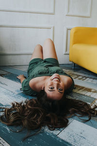 Portrait of smiling woman lying on floor at home