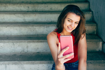 Portrait of a smiling young woman using mobile phone