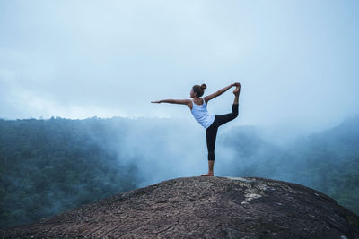 Full length of woman doing yoga on mountain against sky 
