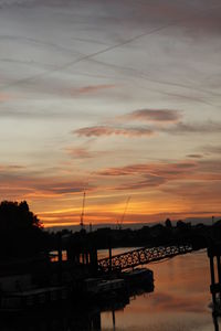 Silhouette bridge over river against sky during sunset