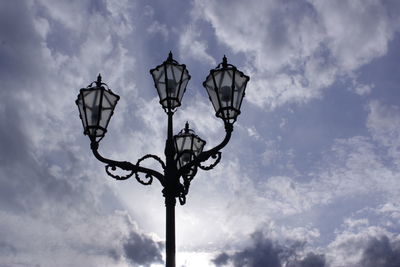 Low angle view of lamp post against cloudy sky