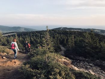 Rear view of people walking on mountain against sky
