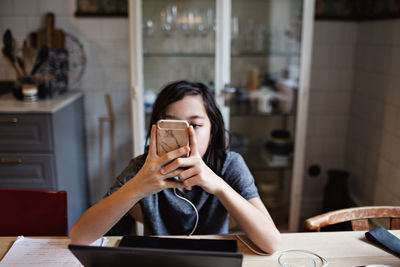 Boy using smart phone while doing homework at home