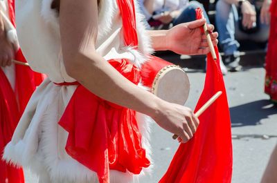 Midsection of man playing drum while standing on street