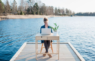 Woman flexible working on a desk on a pier at the beach