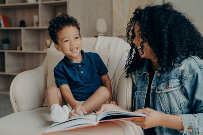 Full length of mother and daughter sitting on book