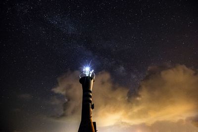 Low angle view of illuminated lighthouse against sky at night