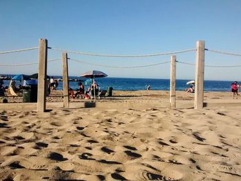 People at beach against clear sky