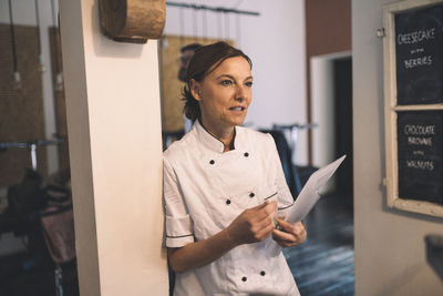 Mature female chef looking away while standing in restaurant