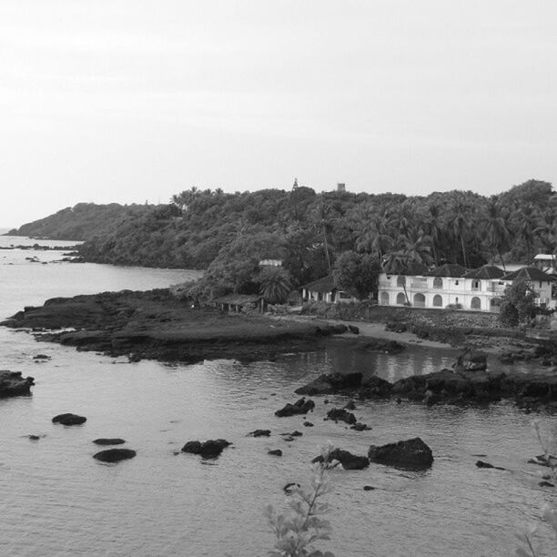 water, built structure, clear sky, tranquil scene, sea, architecture, tranquility, sky, tree, building exterior, nature, rock - object, scenics, mountain, beauty in nature, day, lake, copy space, house, river