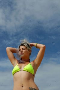 Portrait of woman in bikini standing against sky