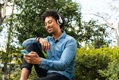 Smiling man using smart phone in park