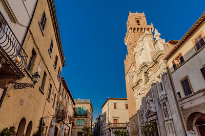 Low angle view of pitigliano cathedral against clear blue sky during sunny day