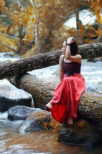 Woman sitting on tree at lake