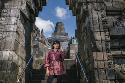 Portrait of woman standing on steps at temple entrance