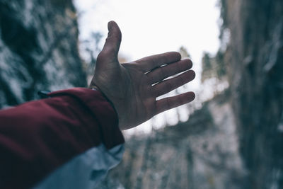 Close-up of human hand against sky