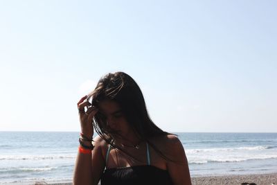 Young woman at beach against clear sky