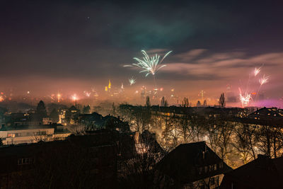 Firework display in city against sky at night