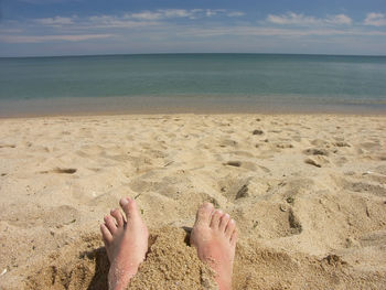 Low section of person on beach against sky