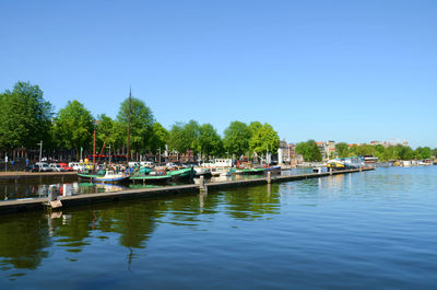 Boats in calm sea against clear sky